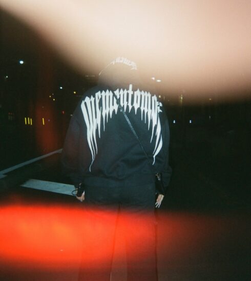 Person in black clothing stands in the dark.